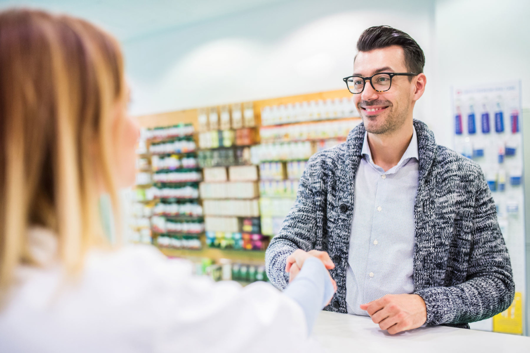 Man with glasses at counter smiling and shaking hands with woman