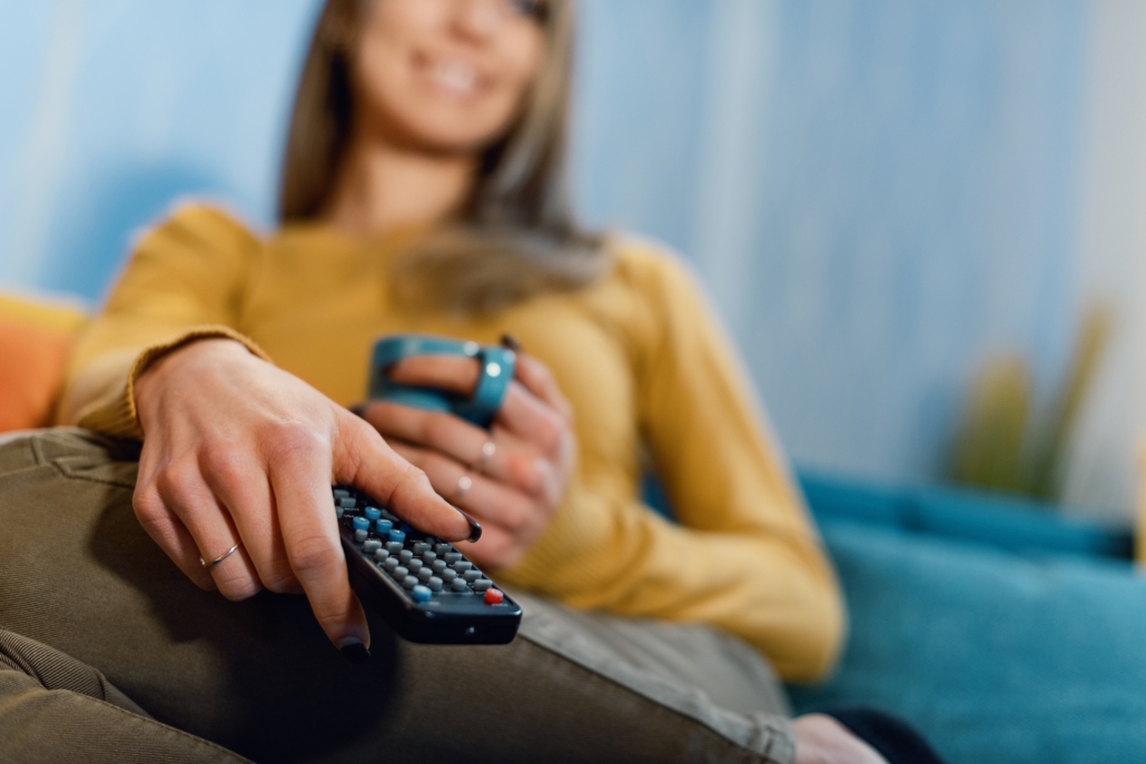 Watch TV - Woman holding a remote control and watching TV